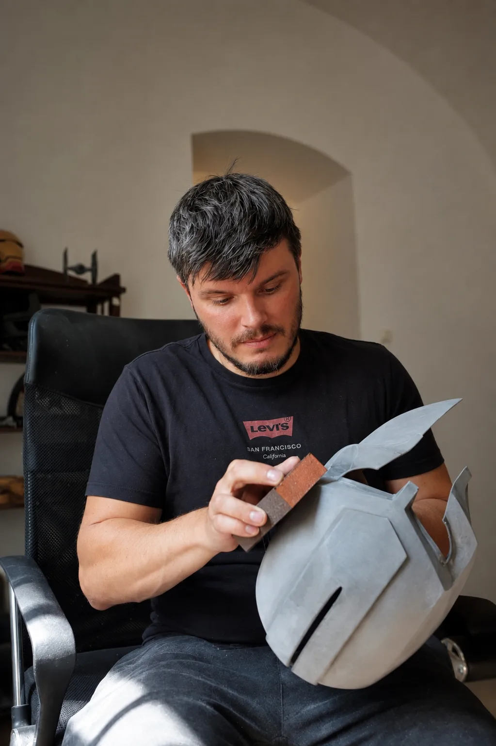 Držím hotovou přilbu s chocholem, v rohu detail 3D tiskárny při tisku helmy Mandaloriana